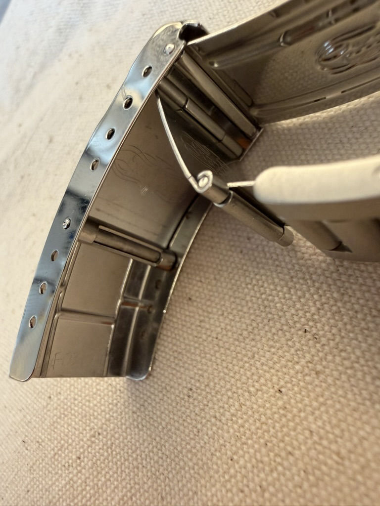 A close-up of a Submariner bracelet clasp, showing its folded steel construction